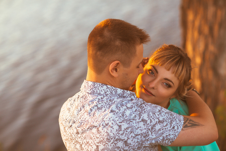 Romantic couple standing  and kissing on background summer lake sunsetの写真素材