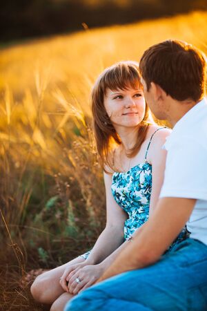 Romantic couple standing  and kissing on background summer meadow sunsetの写真素材