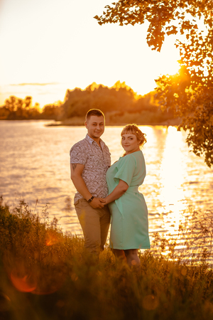 Romantic couple standing  and kissing on background summer lake sunsetの写真素材