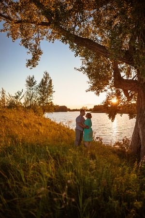 Romantic couple standing  and kissing on background summer lake sunsetの写真素材