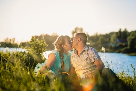 Romantic  couple sit and  kissing  on background summer lakeの写真素材