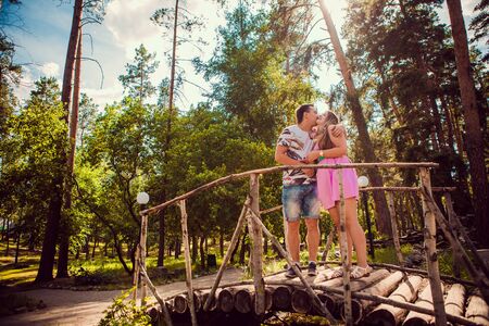 Romantic young couple kissing  and stand to  bridge on background summer forestの写真素材