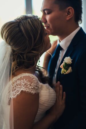 Bride and groom posing  in a hotel room on background windowsの写真素材