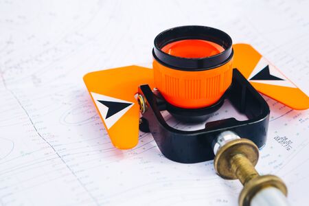 orange theodolite prism  lies on a background of geodetic maps of the areaの写真素材