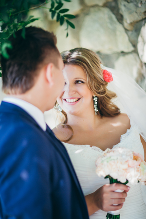 Happy couple  bride and groom embracing they stand on background stone wall close-upの写真素材