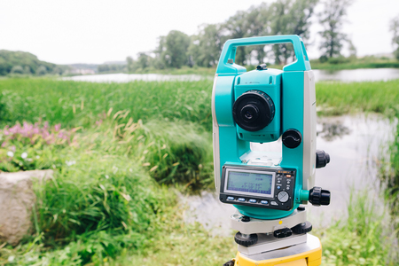 blue surveying  equipment total station on a background of lake and forestの写真素材