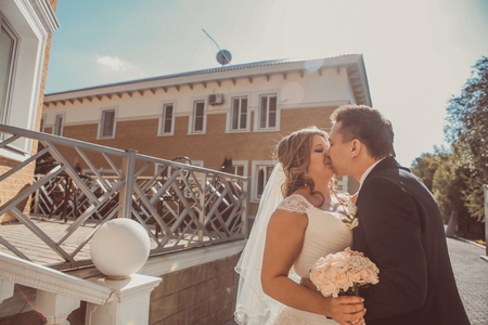 bride and groom embracing they stand on background beautiful architecture of the city full lengthの写真素材