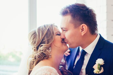 Bride and groom posing  in a hotel room on background windowsの写真素材