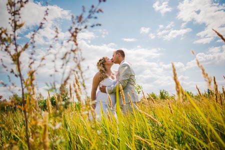 Wedding  beautiful young couple kissing on the background of meadowsの写真素材