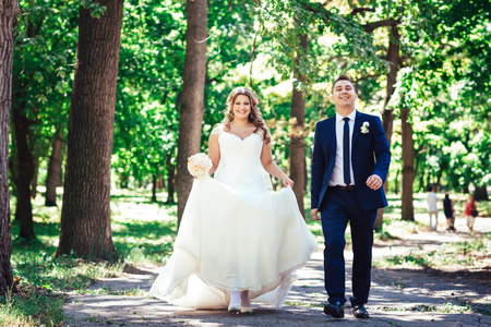 Happy couple bride  and groom walk embracing in a forest full lengthの写真素材
