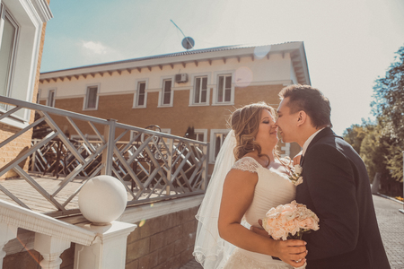 bride and groom embracing they stand on background beautiful architecture of the city full lengthの写真素材