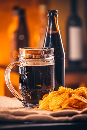 A glass of fresh beer, a bottle  of beer and chips on sackingの写真素材