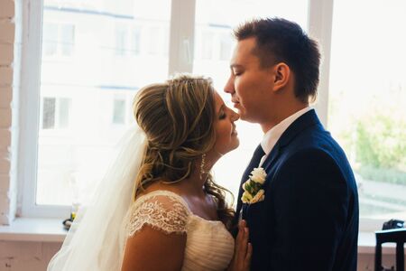 Bride and groom posing  in a hotel room on background windowsの写真素材