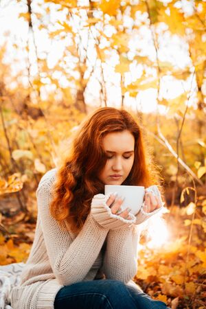 Young woman in a sweater and jeans relaxing drink tea on autumn  backgroundの写真素材