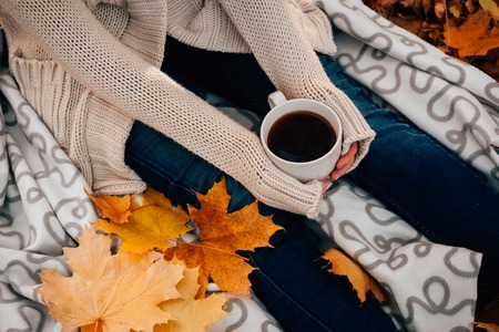 Young woman in a sweater and jeans relaxing drink tea on autumn  backgroundの写真素材