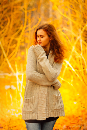 Young woman  in a sweater and jeans stand on autumn backgroundの写真素材