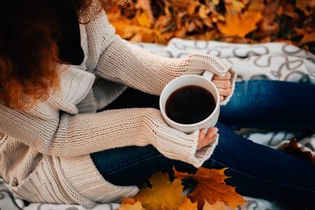 Young woman in a sweater and jeans relaxing drink tea on autumn  backgroundの写真素材