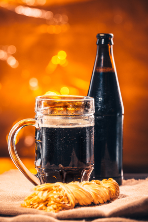 bottle and glass of fresh dark beer with smoked cheese braid on sackingの写真素材