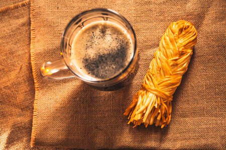 A glass of fresh dark  beer with smoked cheese plait on sackingの写真素材