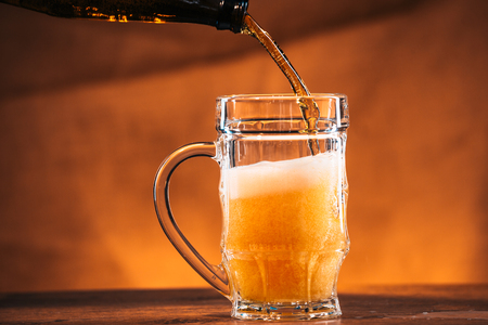 bright  beer is  poured into a glass mugの写真素材