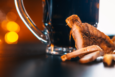 glass of fresh beer and dried chicken on wooden  tableの写真素材