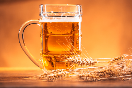 mug of light beer with  ears of wheat on the wooden tableの写真素材