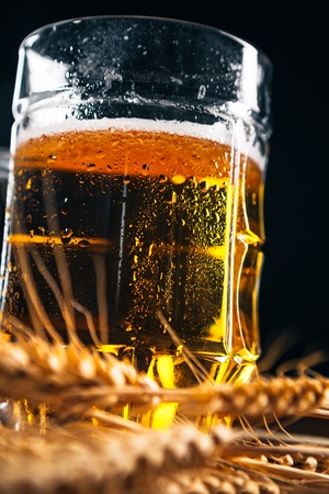 close-up  mug of light beer with ears of wheat on the wooden tableの写真素材