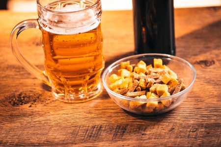 glass of fresh bright beer and crackers on  wooden tableの写真素材