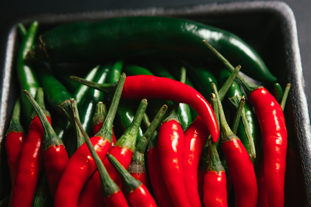 red and green chili peppers  close up on wooden backgroundの写真素材