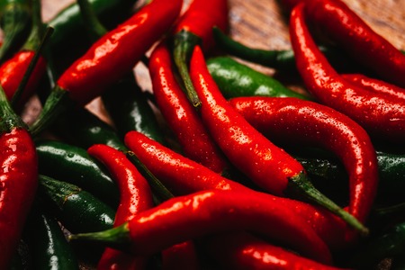 red and green chili peppers  close up on wooden backgroundの写真素材