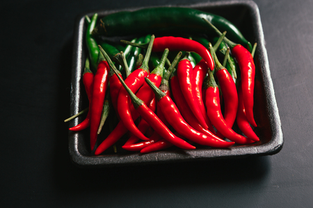 red and green chili peppers  close up on wooden backgroundの写真素材