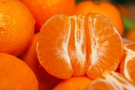 fresh peeled  tangerine segments close up on a background of orange mandarinsの写真素材