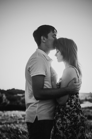 Black white photography romantic couple standing  and kissing on background summer meadow sunsetの写真素材
