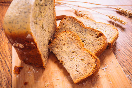 Close slice of  fresh bread with poppy seeds on a wooden backgroundの写真素材