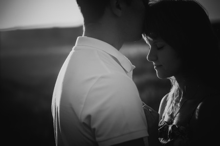 Black white photography romantic couple standing  and kissing on background summer meadow sunsetの写真素材