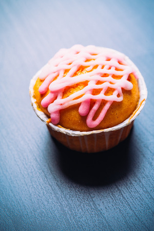 cupcake with pink frosting on  a wooden backgroundの写真素材