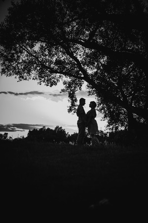 Black white photography romantic couple standing  and kissing on background summer meadow sunsetの写真素材
