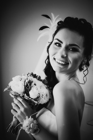 Black white photography beautiful young happy bride standing near the windowの写真素材