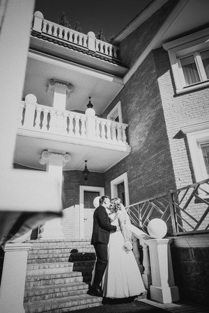 Black white  photography bride and groom embracing they stand on background beautiful architecture of the city full lengthの写真素材