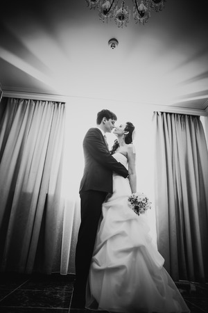 Black white photography beautiful young  couple standing near the windowの写真素材