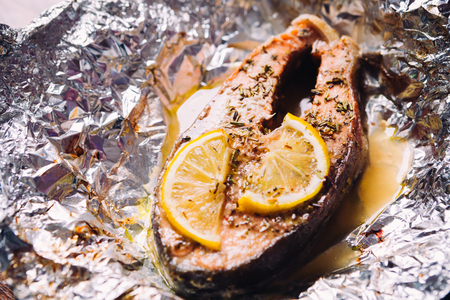 fish steak baked with lemon and herbs  in foilの写真素材
