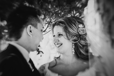 Black white photography happy couple  bride and groom embracing they stand on background stone wall close-upの写真素材
