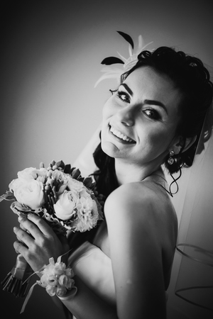 Black white photography beautiful young happy bride standing near the windowの写真素材