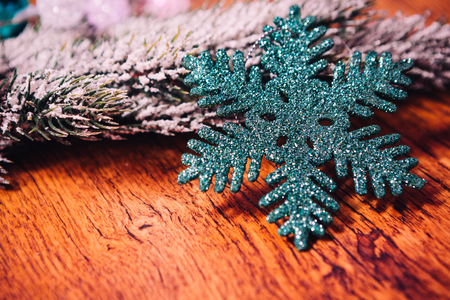 Spruce branches in the snow,  and blue snowflake wooden backgroundの写真素材