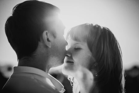 Black white photography romantic couple standing  and kissing on background summer meadow sunflower  sunsetの写真素材