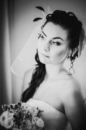 Black white photography beautiful young happy bride standing near the windowの写真素材