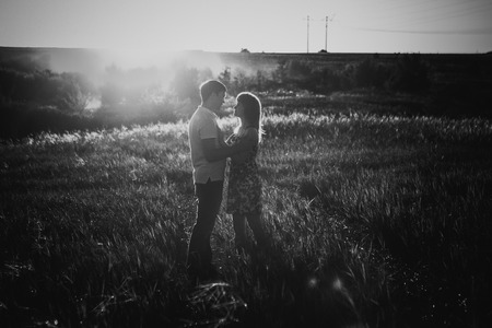 Black white photography romantic couple standing  and kissing on background summer meadow sunsetの写真素材