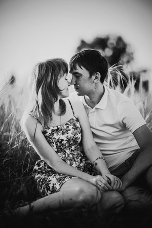 Black white photography romantic couple standing  and kissing on background summer meadow sunsetの写真素材