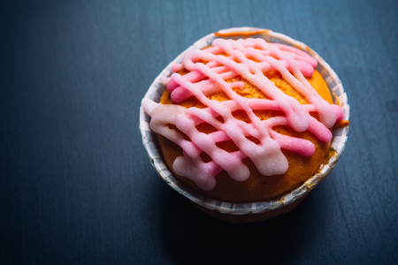 cupcake with pink frosting on  a wooden backgroundの写真素材