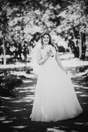 Black white photography stylish beautiful happy bride holding   bouquet of  flowers on a background of trees in the summer park close-upの写真素材